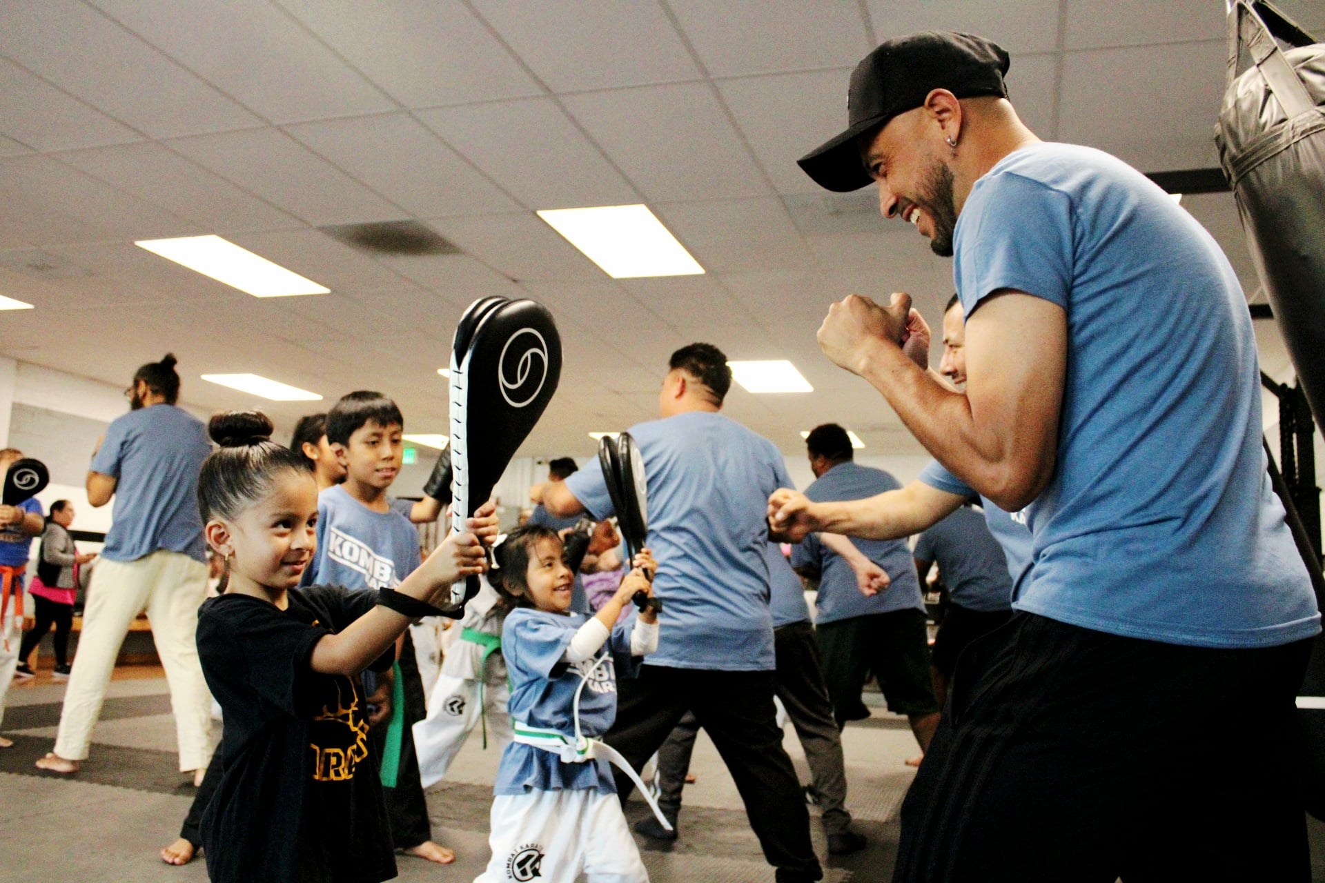 Instructor guiding young kids through punching drills during a beginner karate class at Kombat Karate in Long Beach, CA