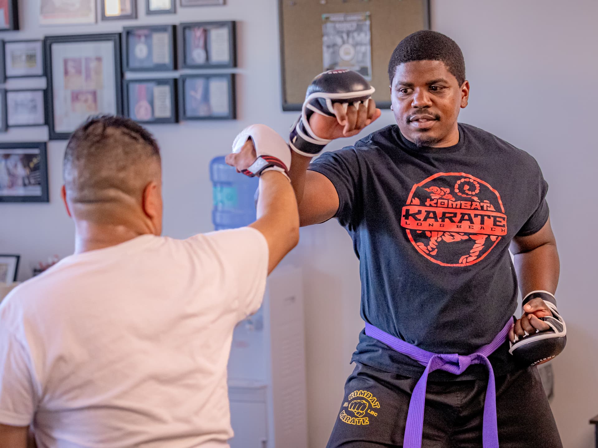 Teen karate student drilling strikes on pads with an instructor in Long Beach, CA